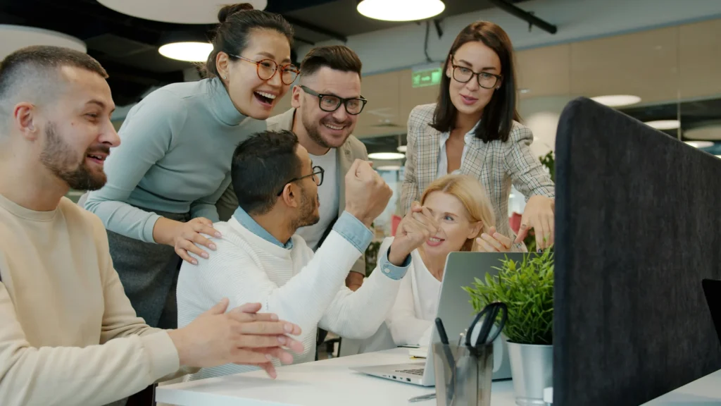 Team celebrating a result at a desk