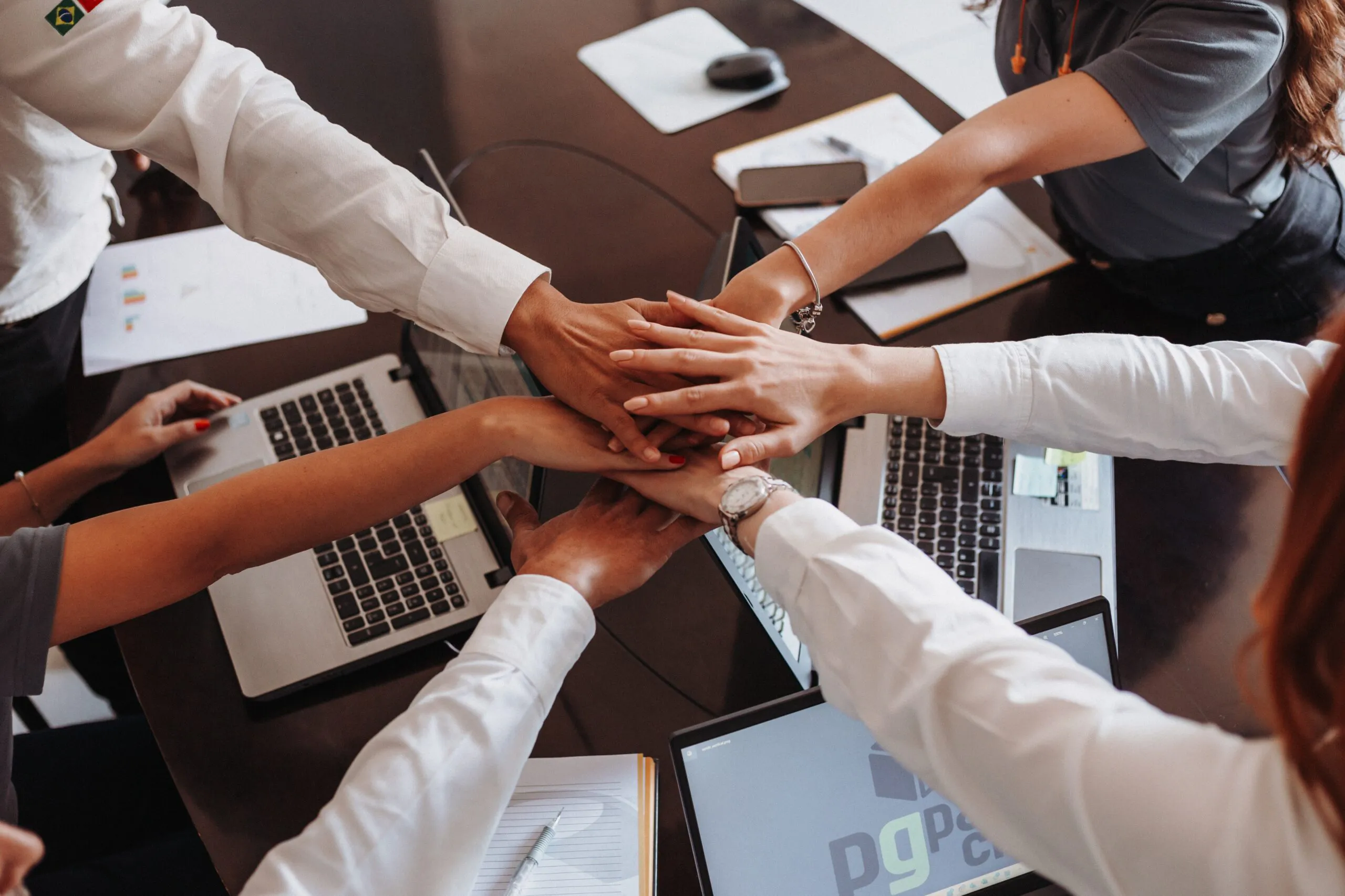 Colleagues stacking hands above a table