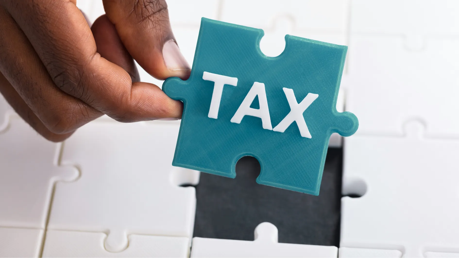 Hand placing a puzzle piece labelled tax